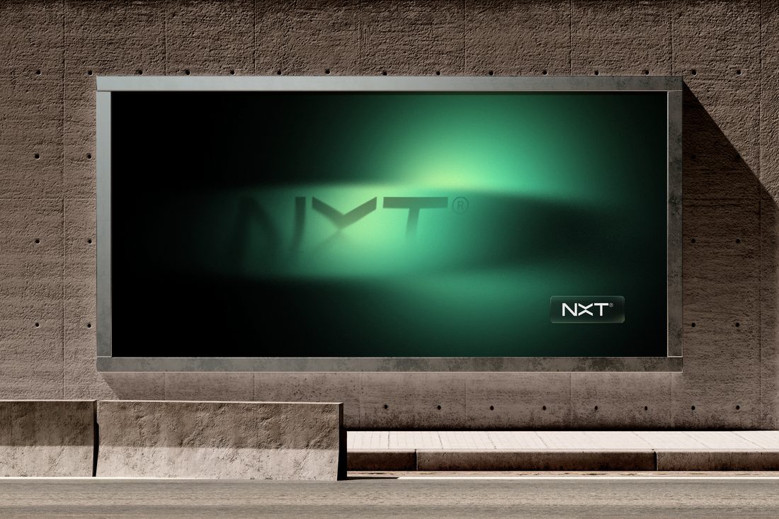 Cartel de vía pública de marca NXT sobre pared de cemento